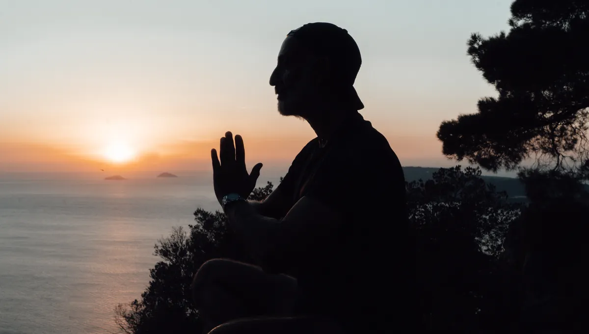 Person meditating above the sea at sunset